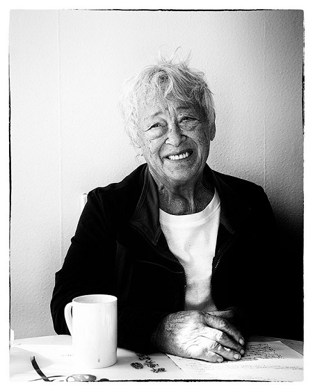 a white-haried women sitting at a table, smiling